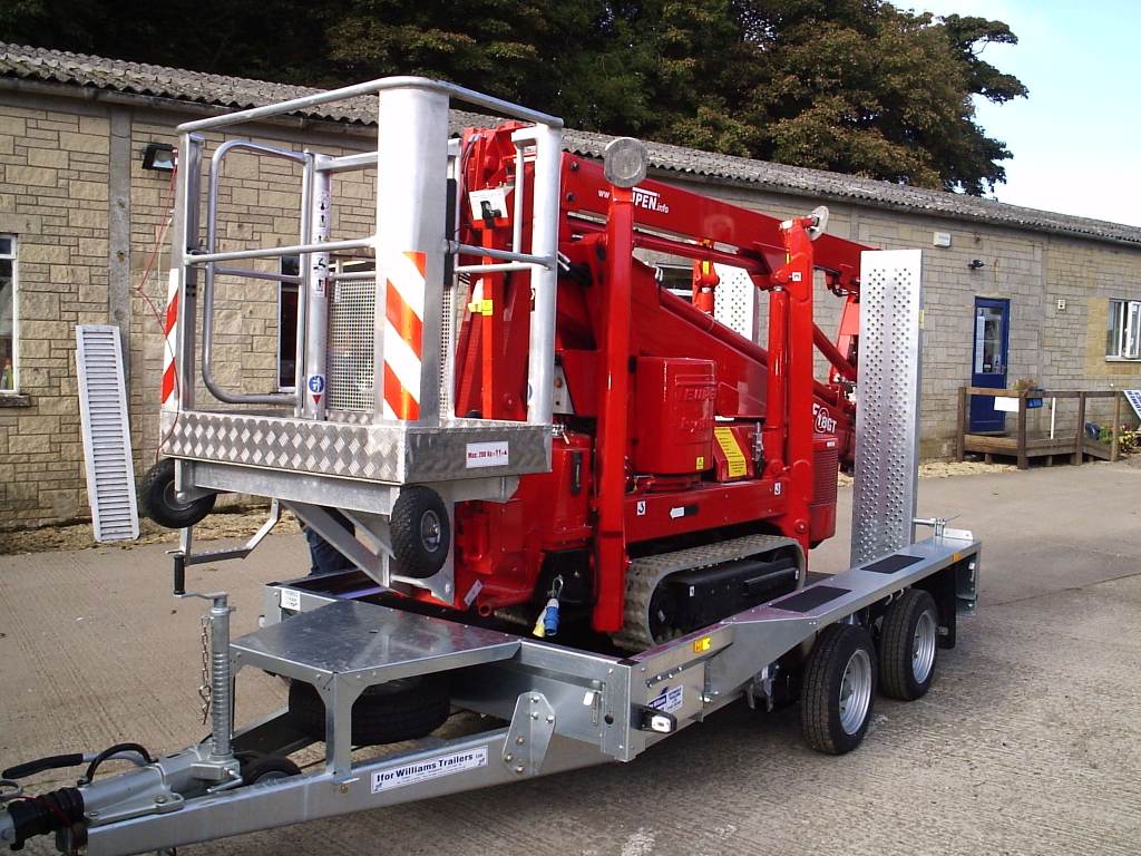 Red construction vehicle on a trailer in front of a building