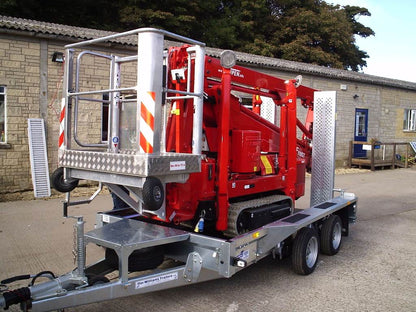 Red construction vehicle on a trailer in front of a building