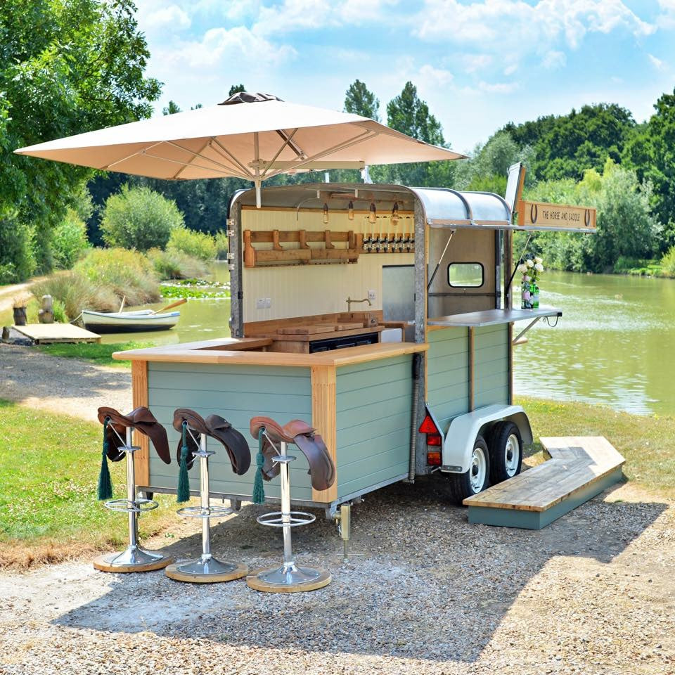 Portable outdoor kitchen trailer with seating area by a lake